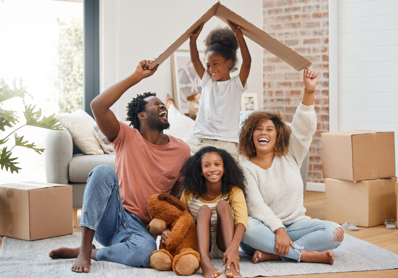 A family is sitting on the floor with boxes.