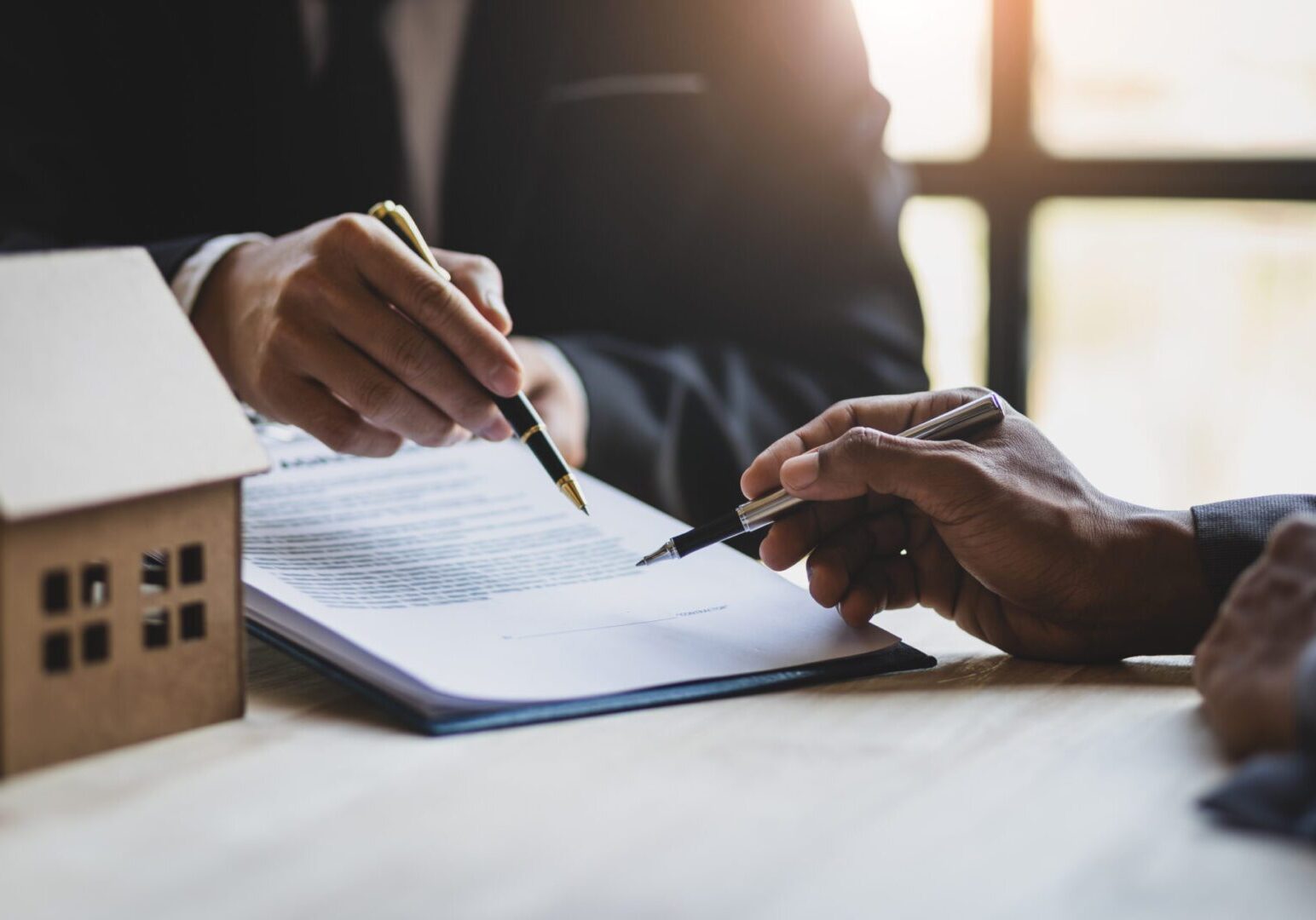 A person is signing papers on top of a table.